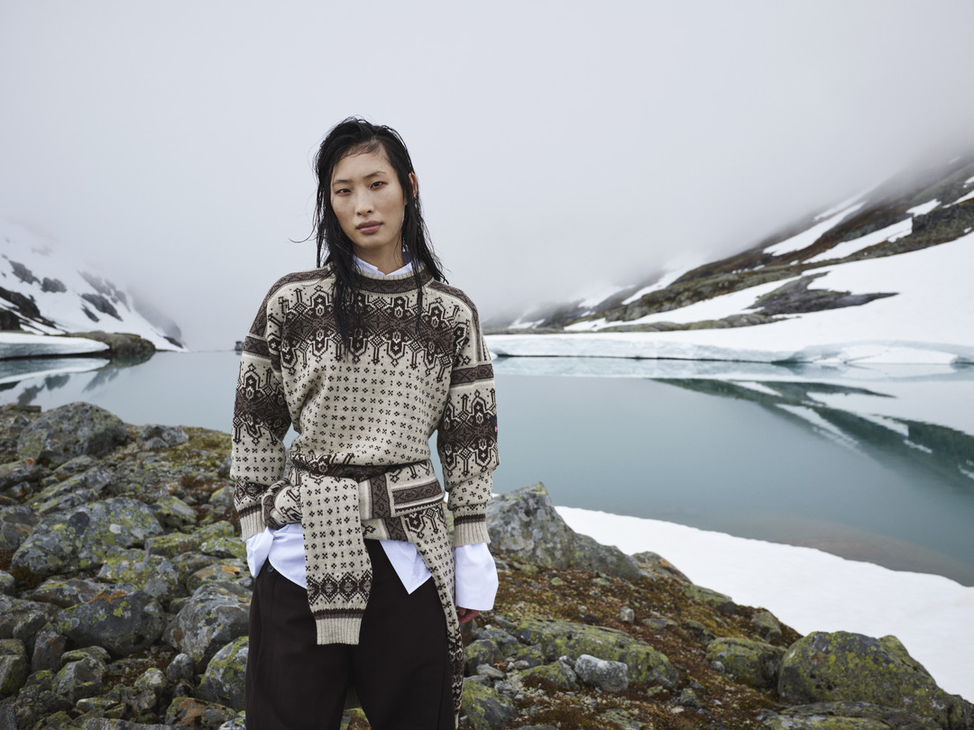 Dale of Norway Albertville sweater in beige and brown with traditional Norwegian pattern and matching belt, photographed by a mountain lake in Norway